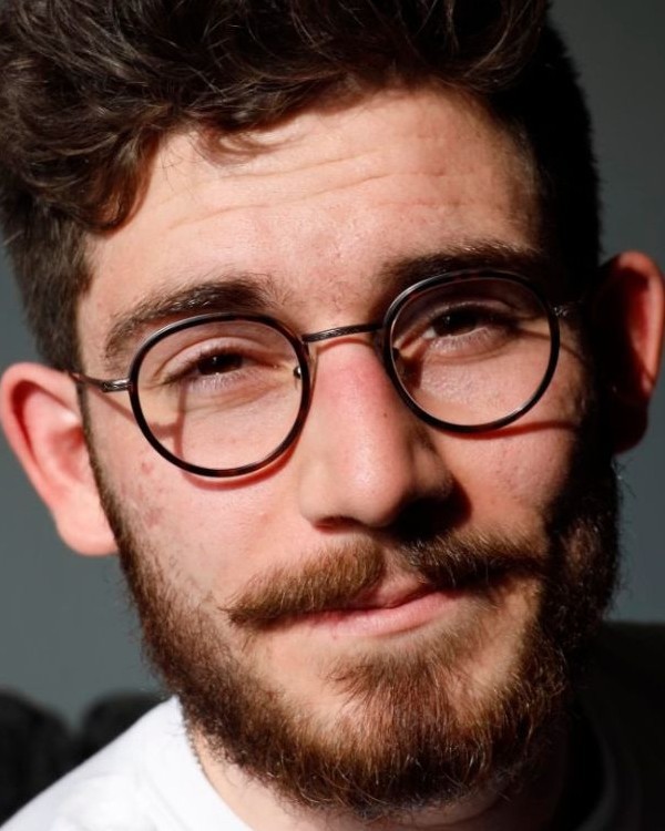 A picture of a person with brown hair, a beard, and glasses smiling